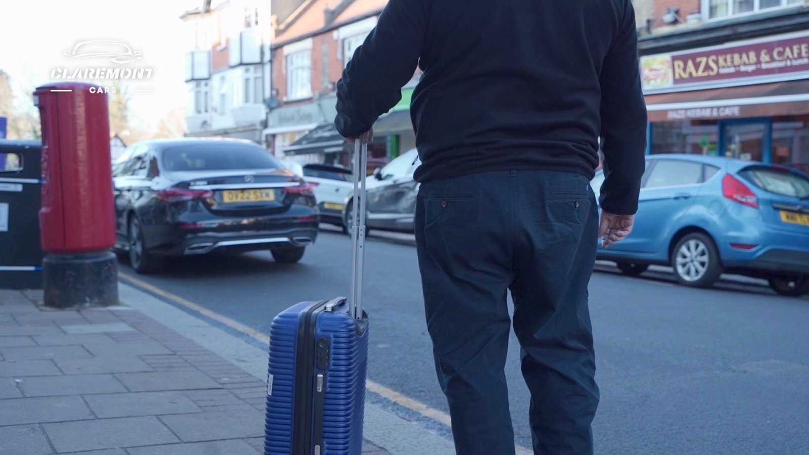 A driver loading a suitcase into the boot