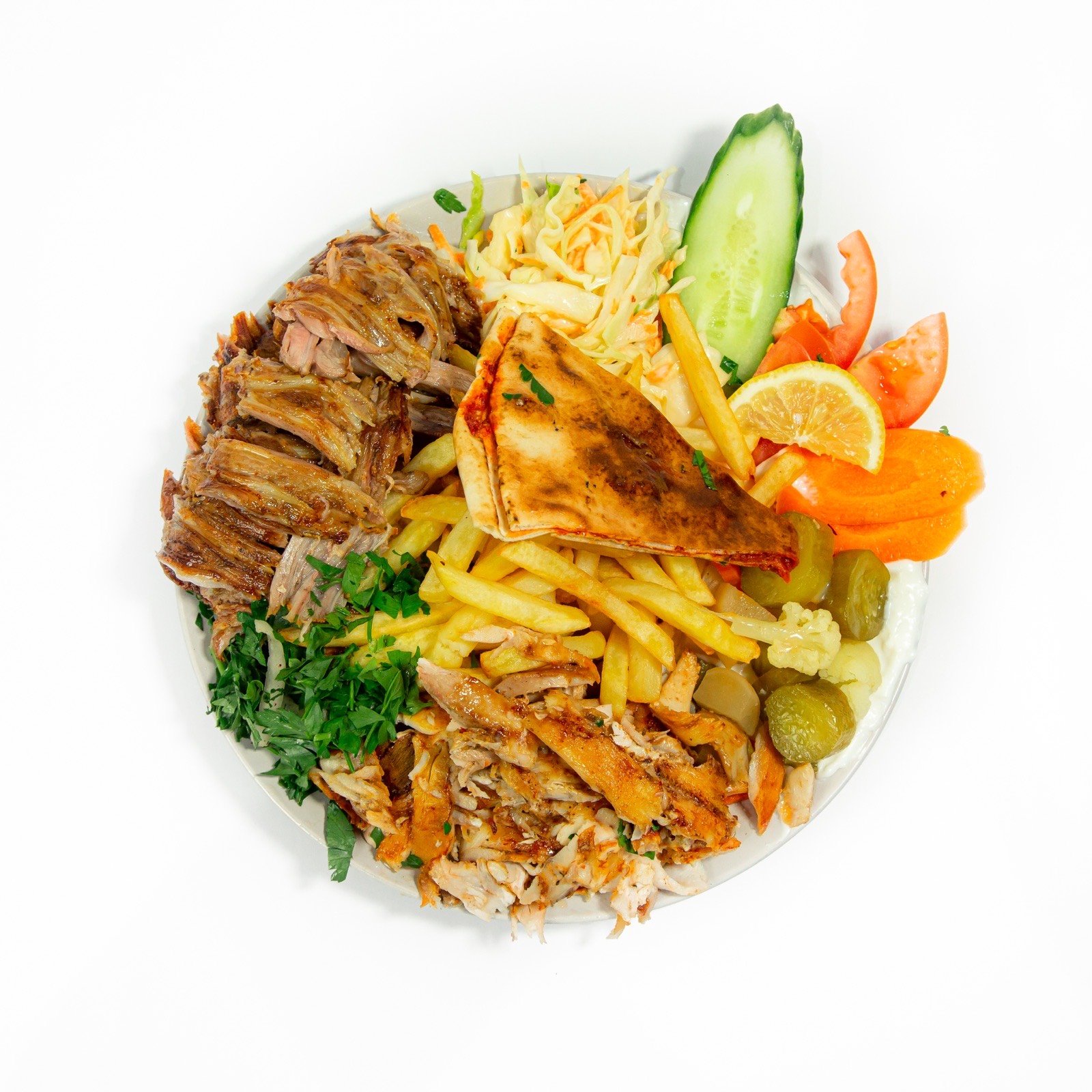 A mixed shawarma plate with chips, salad and pickles, shot from above on white