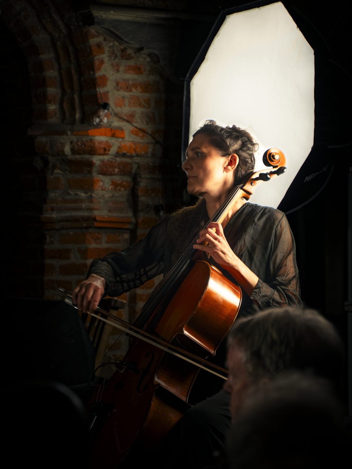 The cellist playing under a soft white light