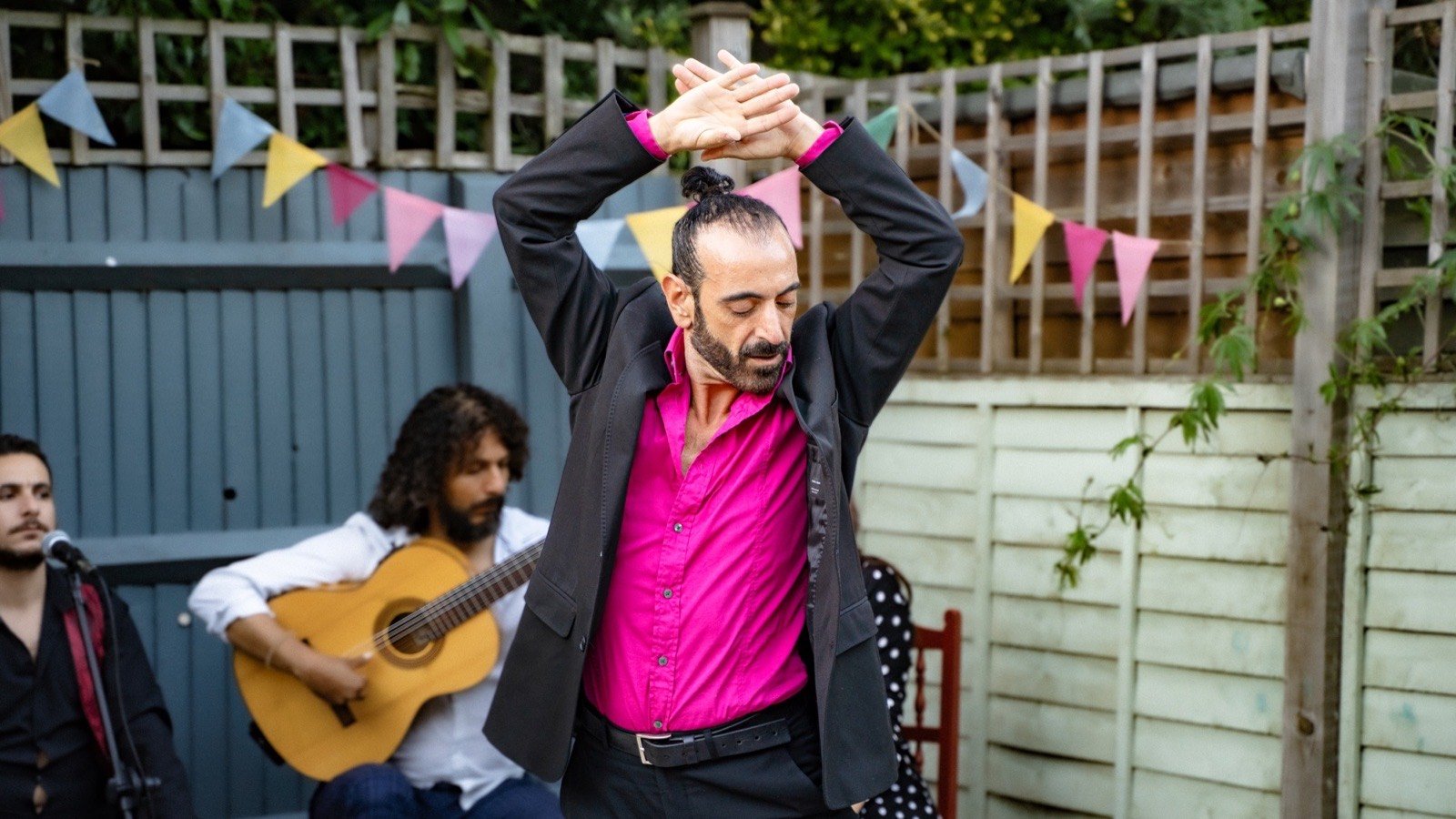 The dancer, arms raised, with the guitarist