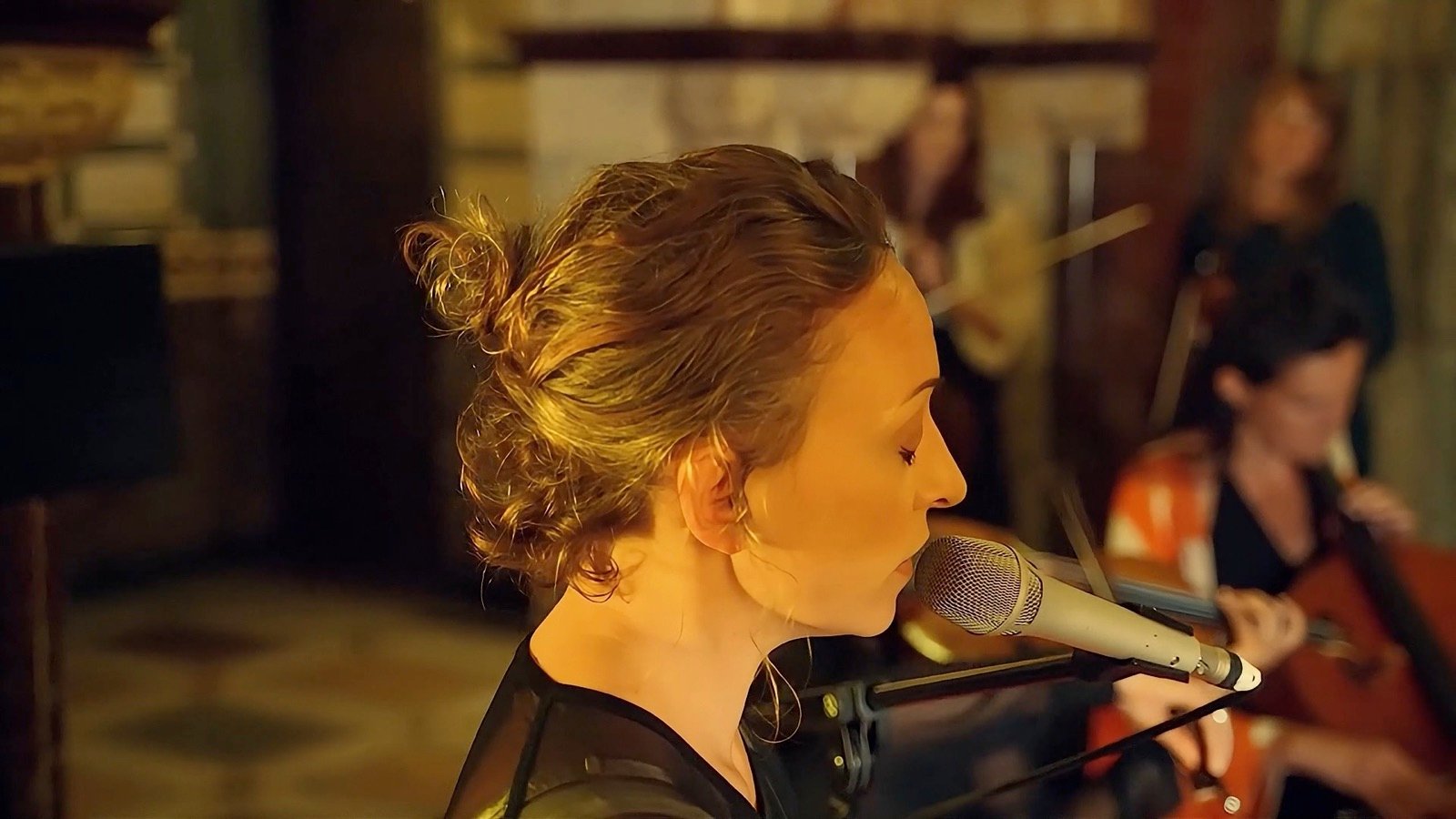 Singing, eyes down, in the lamplight