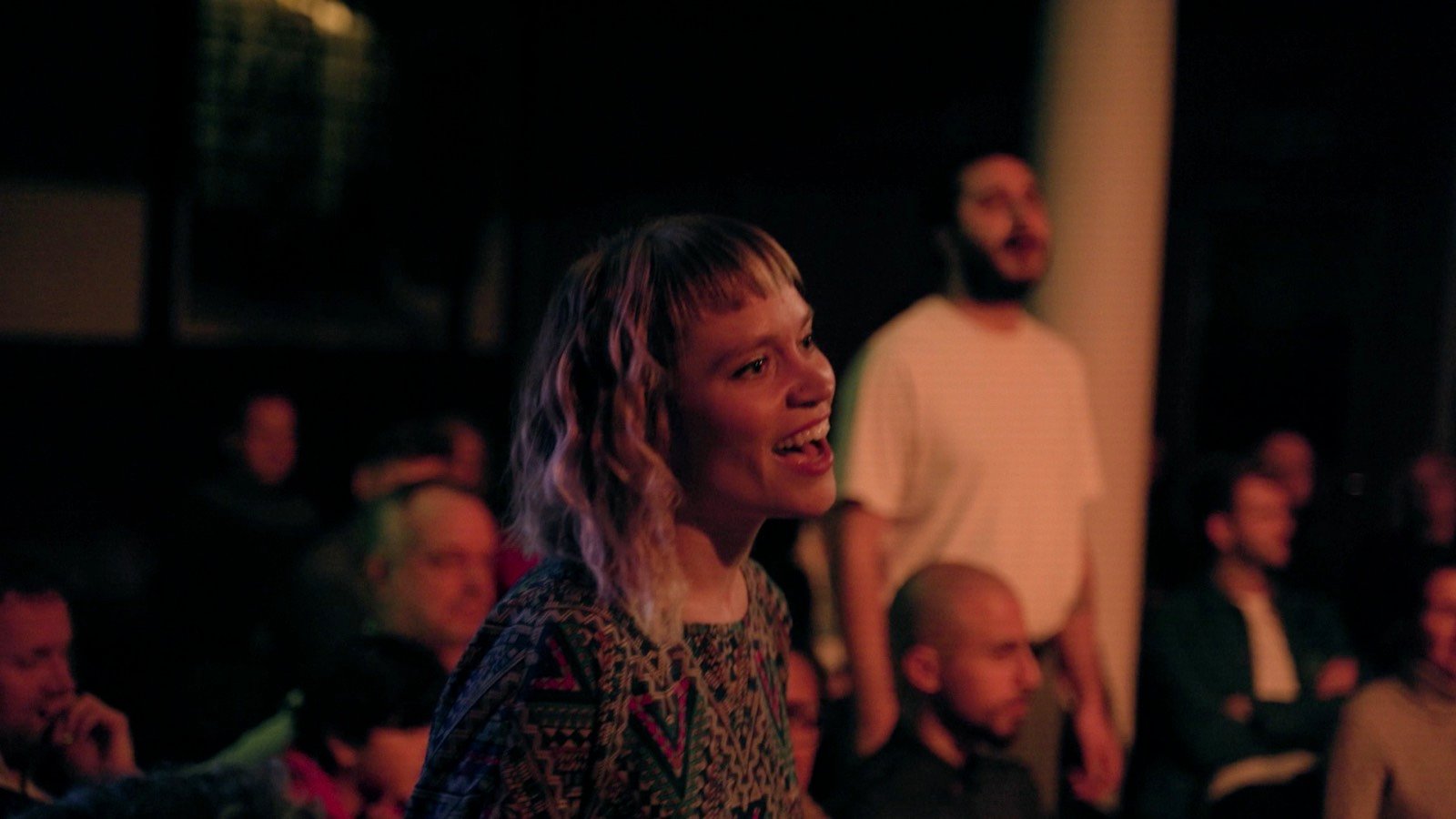 A singer performing among a seated audience in a warm-lit church