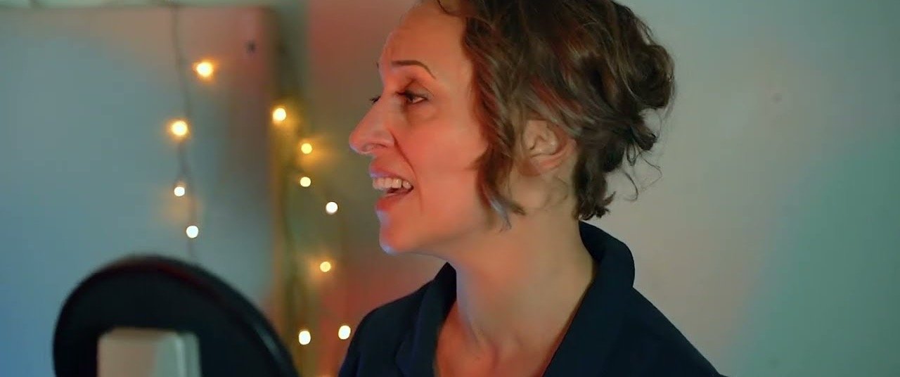 A singer at a microphone in front of fairy lights
