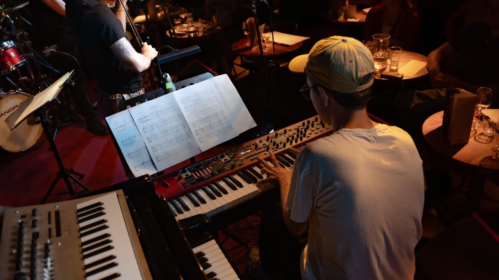 A keyboard player on stage, seen from above, with sheet music