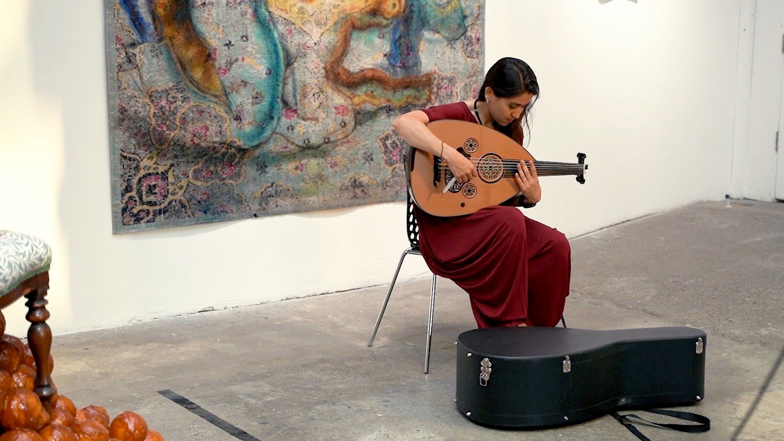 Alone in the white room, the oud case at her feet