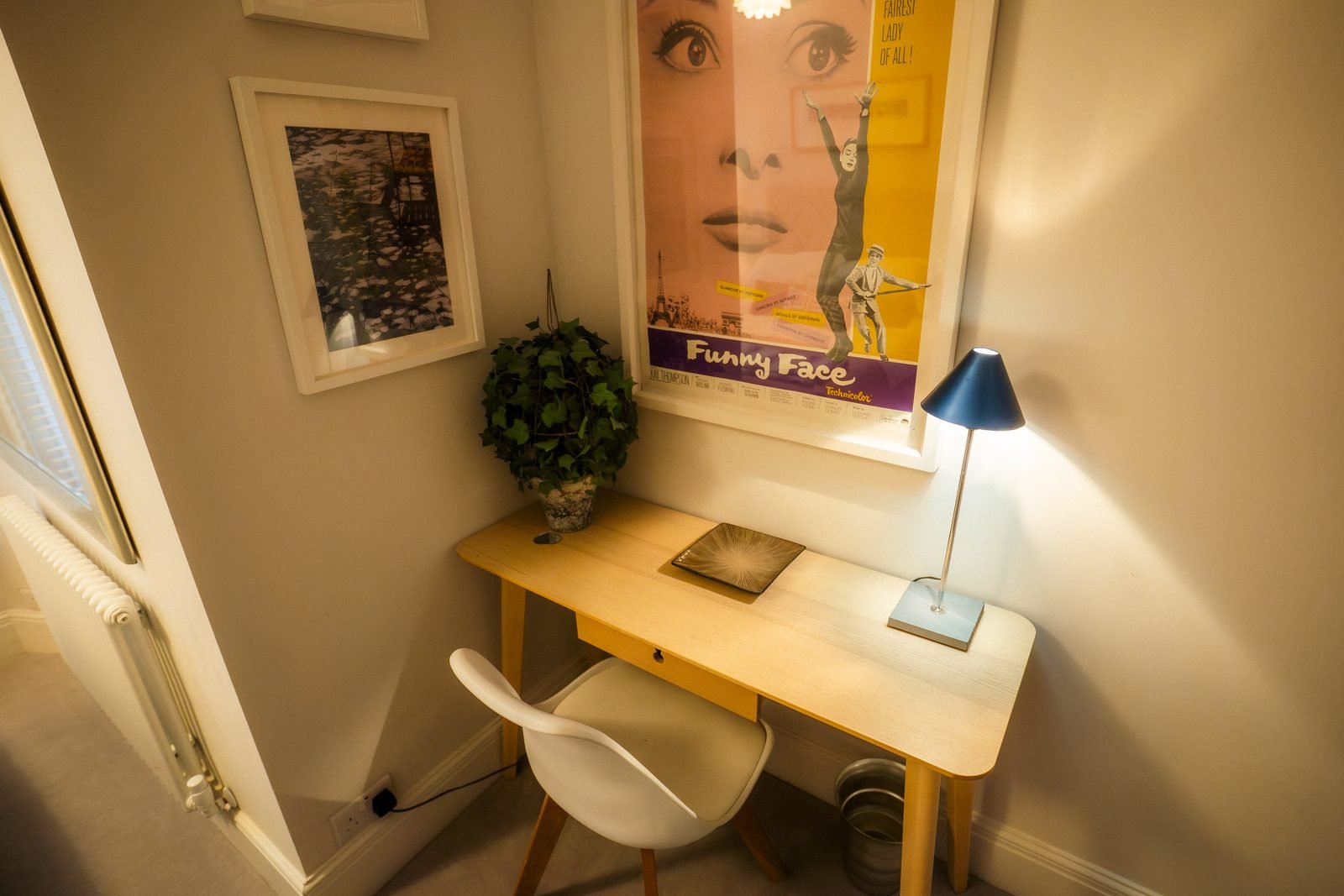 A small writing desk under a framed film poster