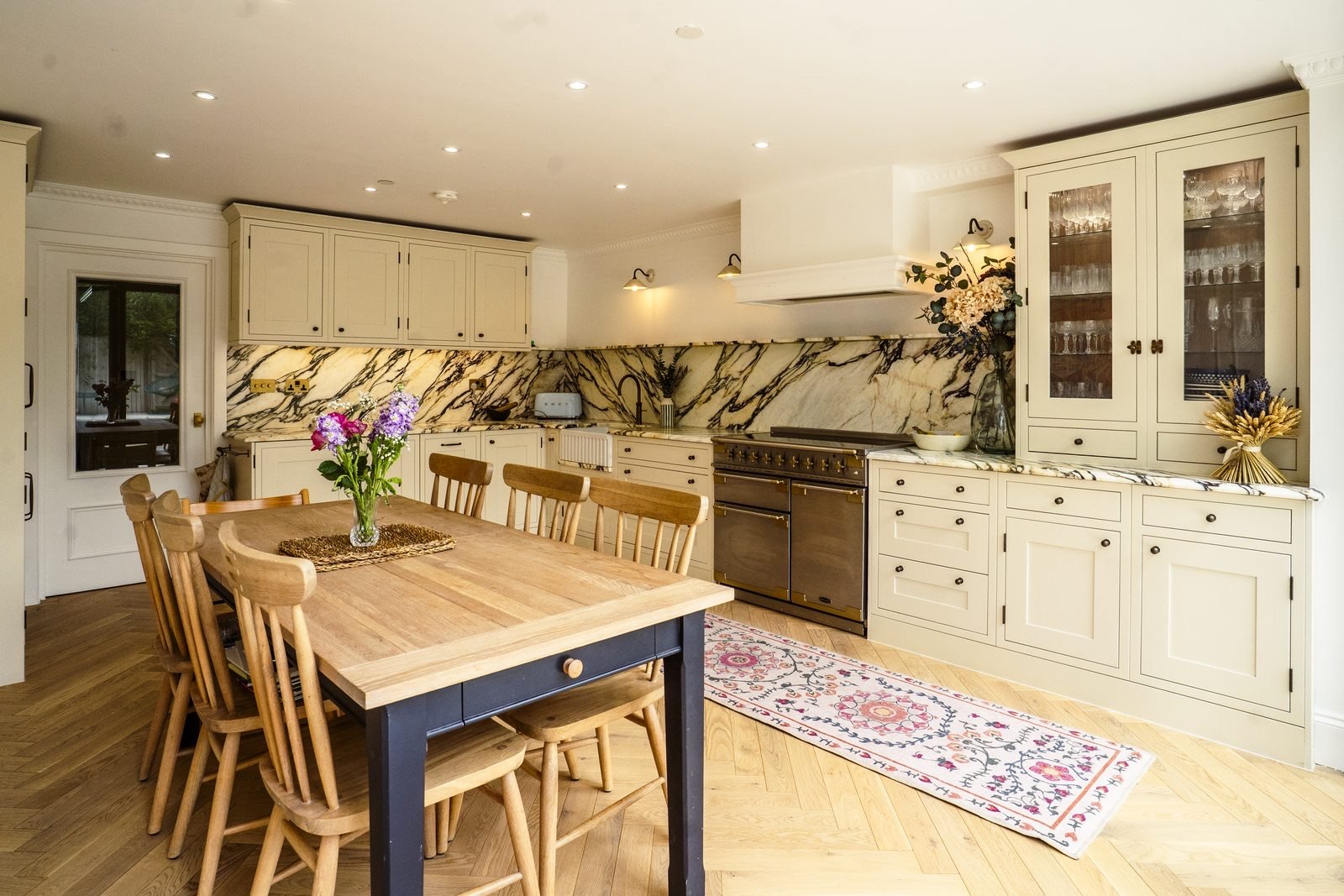 A kitchen with a marble splashback and a wooden dining table