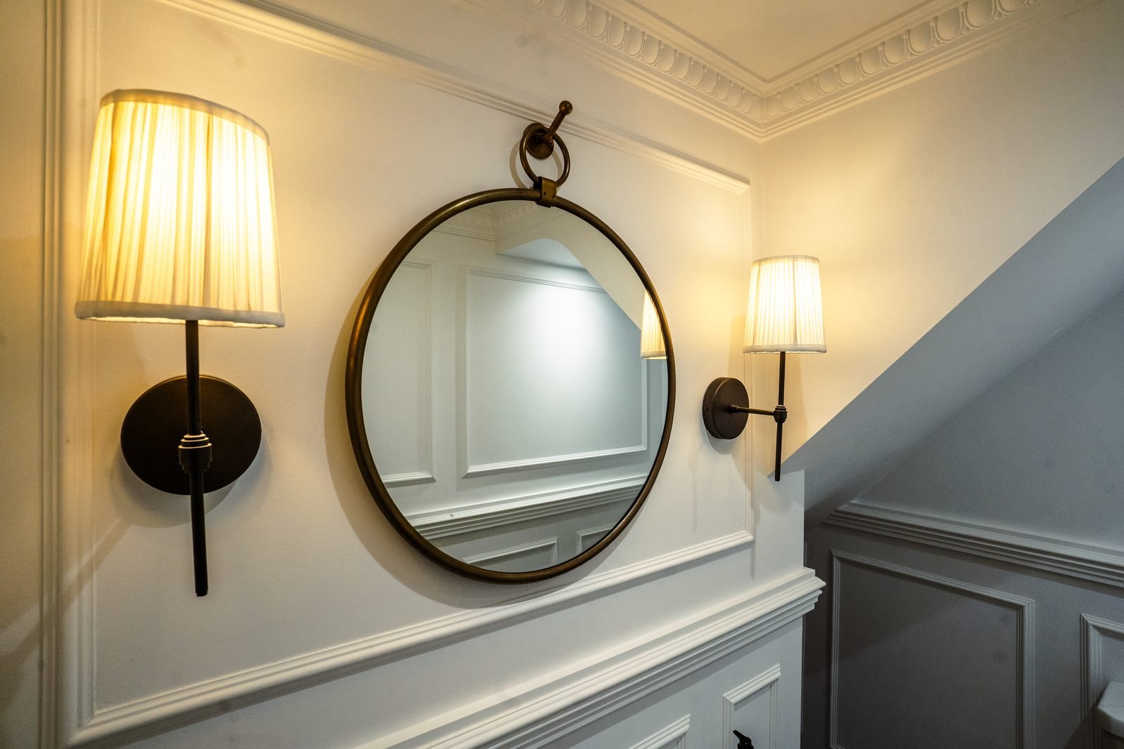 A round mirror between two wall lights