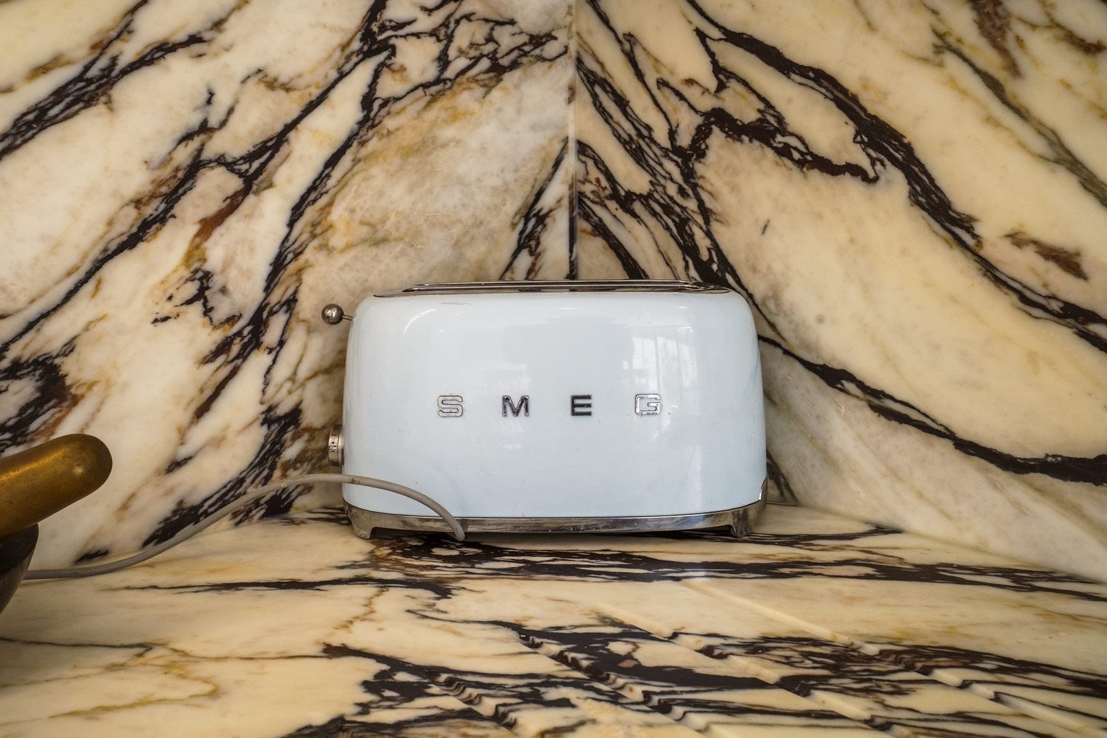 A white toaster against a marble splashback