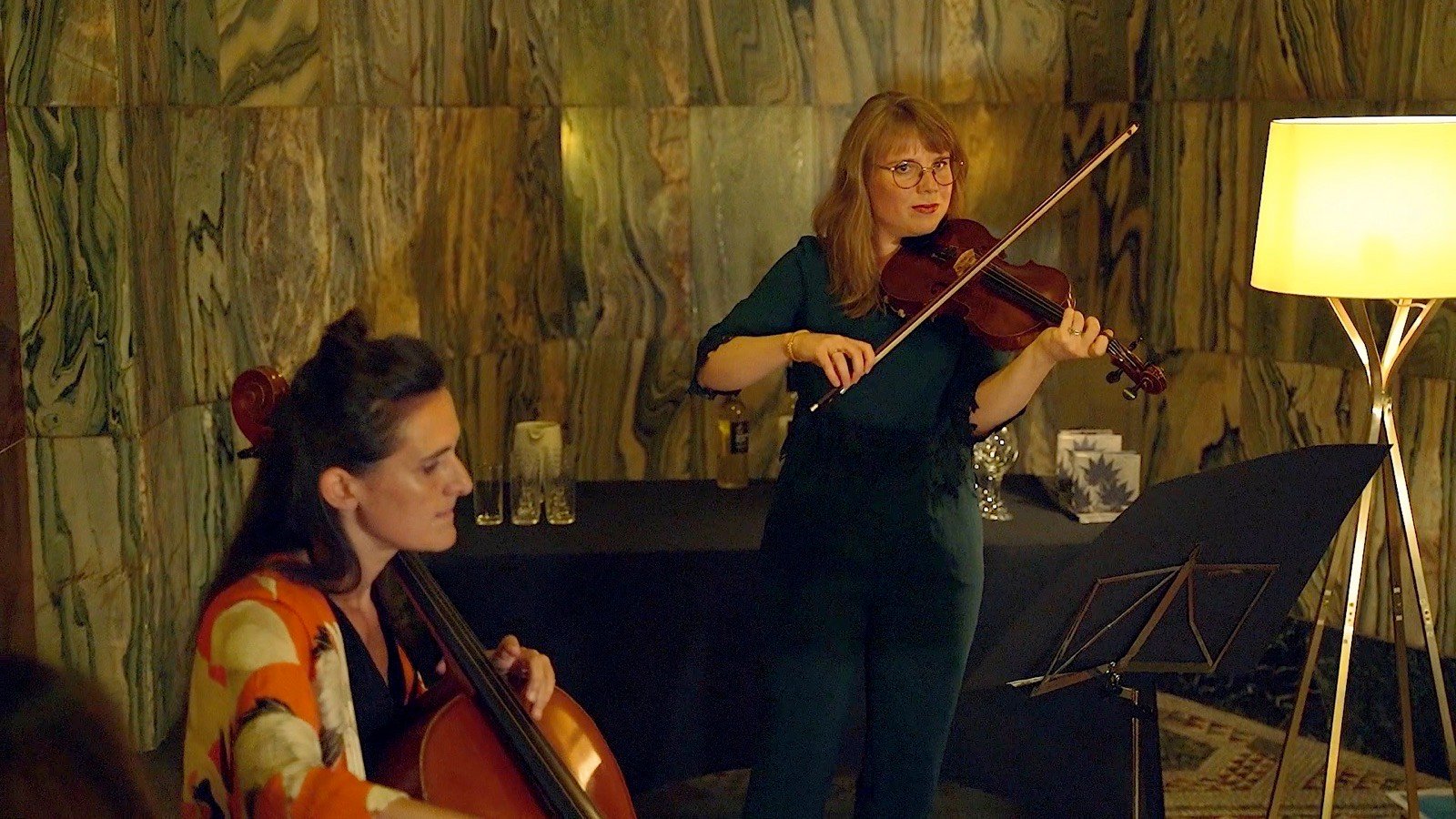 A violinist and a cellist playing by a lamp in Fitzrovia Chapel