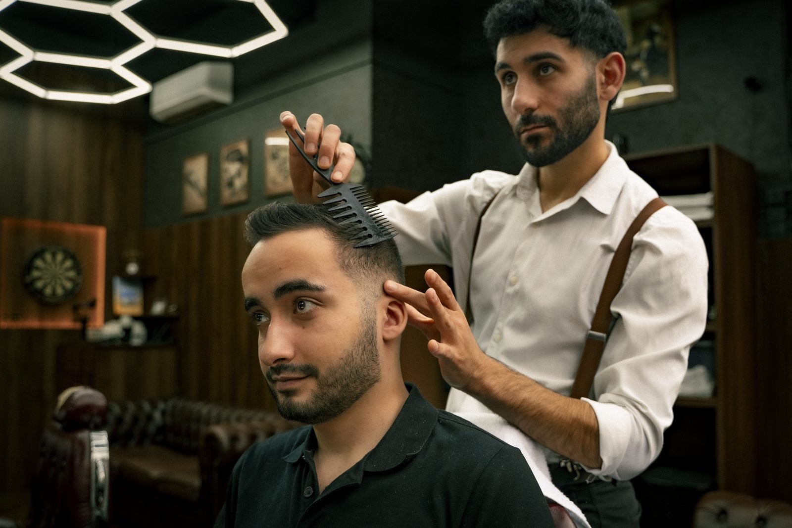 A barber combing a client’s hair under the hexagon lights