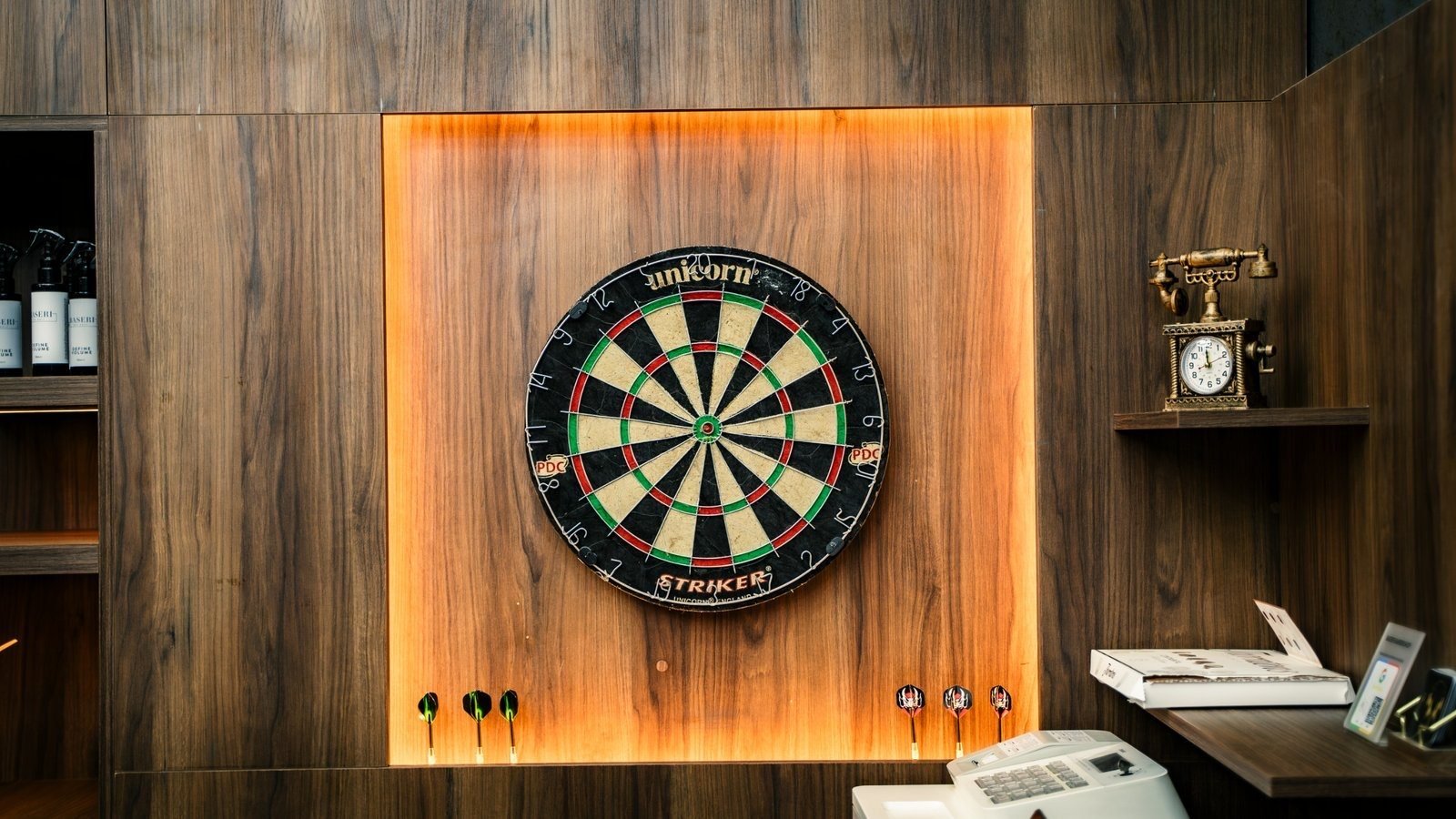 Joinery at The Twins Barbers: a dartboard set in a lit wooden alcove