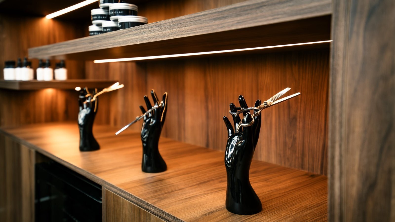 Joinery at The Twins Barbers: hand stands holding scissors on a lit wooden counter