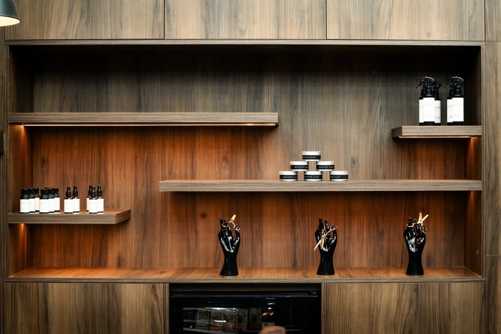 Joinery at The Twins Barbers: wooden shelving with products and hand stands