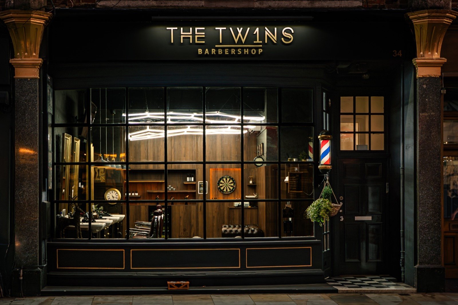 The shopfront at night, its gold sign above a lit window