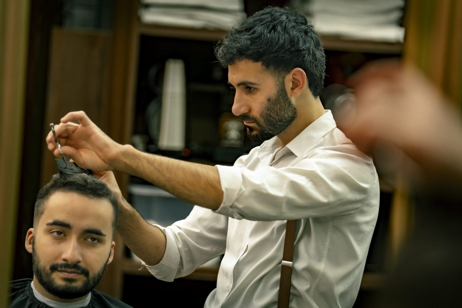 A barber at work, his client facing the camera