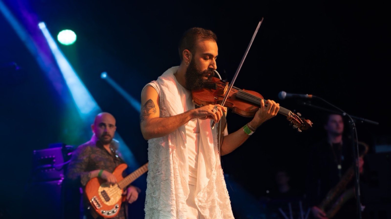 A violinist in white under blue stage lights