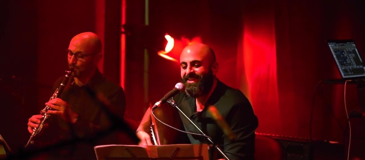 A clarinettist and a singer with an oud under red light